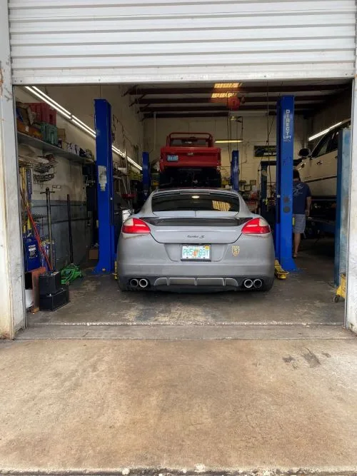 A silver Porsche on the lift inside a service bay