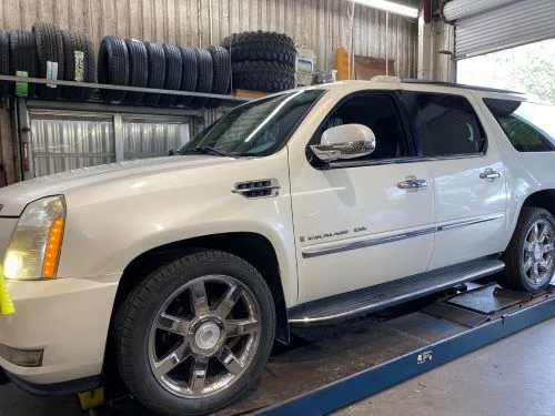 A white Cadillac Escalade on the alignment rack